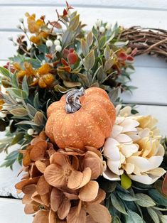 a wreath with flowers, leaves and a ring on it