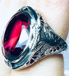 Simulated Red Ruby Ring GG Design#2 Custom Made Inspired by Victorian era designs, we have this lovely Antique filigree reproduction ring in sterling silver. There is 4 filigree flowers around the edge of the ring, notice the filigree which extends down the band. This well made setting is sterling silver and is marked 925. This is an eye popping, stunning, bezel set 16ct Simulated red ruby gemstone. This gorgeous gemstone is 17mm x 13mm in dimensions; just shy of 3/4th of an inch long by 1/2 inc Classic Red Ruby Ring, Oval Cabochon, Classic Red Ruby Ring With Oval Cabochon, Collectible Red Rings With Polished Finish, Heirloom Red Signet Ring With Polished Finish, Classic Red Signet Ring For Formal Occasions, Classic Red Engraved Jewelry, Collectible Red Engraved Ring, Formal Polished Red Ruby Ring, Formal Red Ruby Ring With Polished Finish