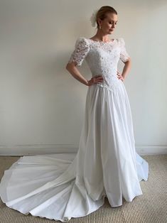 a woman in a white wedding dress is standing on the floor with her hands on her hips