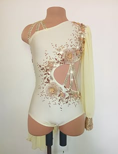 a white bodysuit with gold sequins and flowers on the back, sitting on a mannequin