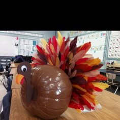 a chocolate turkey sitting on top of a wooden table in front of a class room