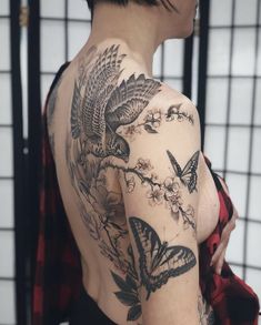 the back of a woman's shoulder with butterflies and flowers tattooed on her arm