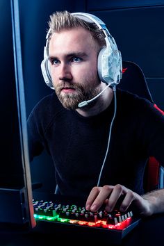 a man wearing headphones sitting in front of a computer keyboard with his hands on the keyboard