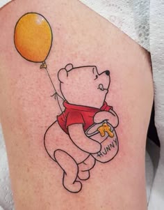 a tattoo with a bear holding a balloon on it's thigh and eating cheese