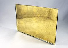 a mirror that is on top of a white surface with gold foiled glass covering it