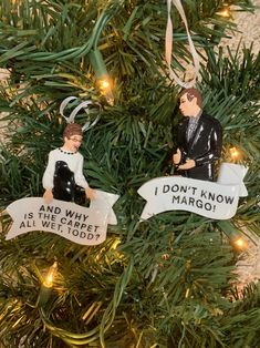 two ornaments hanging from a christmas tree with words on them that read, i don't know and why is it all we need?