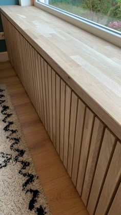 a window sill sitting on top of a wooden floor next to a white rug