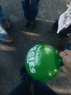 a person holding a green frisbee in their hand with other people standing around