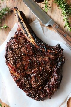 a piece of meat sitting on top of a white plate next to a knife