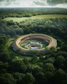 an aerial view of a circular building in the middle of a green field with trees around it