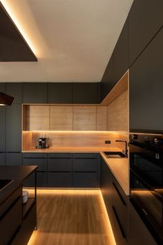 a modern kitchen with wooden cabinets and black counter tops is lit by recessed lighting