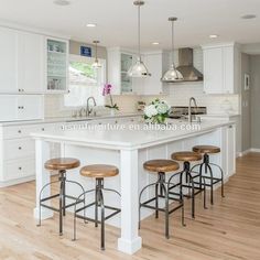 a large kitchen with white cabinets and wooden stools in front of the center island