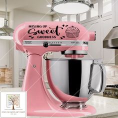 a pink mixer sitting on top of a kitchen counter next to a cupcake maker