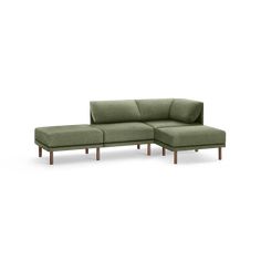 a green sectional couch sitting on top of a wooden table