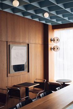 an empty conference room with wooden tables and chairs in front of a large painting on the wall