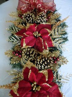 the table is covered with red and gold ribbons, pine cones, and other decorations