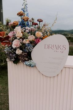 a sign that says drinks on it next to some flowers