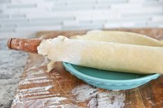 a dough roll sitting on top of a blue plate next to a rolling pin in a bowl