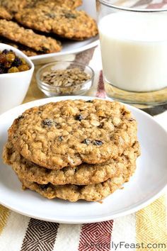 three oatmeal cookies on a white plate next to a glass of milk