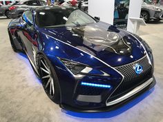 a blue sports car is on display in a showroom with other cars behind it