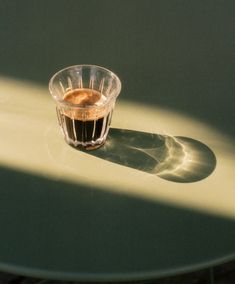 a cup of coffee sitting on top of a table next to a shadow from the sun