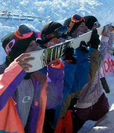 a group of people standing on top of a snow covered slope holding up skis