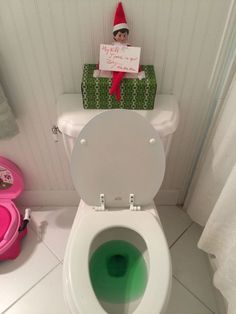 an elf is sitting on top of the toilet in the bathroom with green water inside