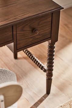 a wooden table with two drawers and a chair next to it on a hard wood floor