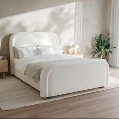 a white bed sitting in a bedroom on top of a hard wood floor next to a window