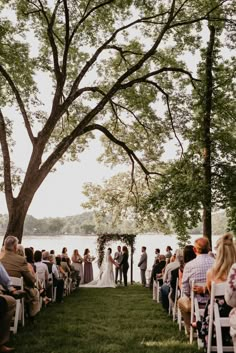 a couple getting married under a tree by the water