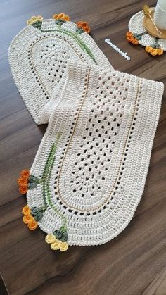 two crocheted doily with flowers on the floor next to eachother