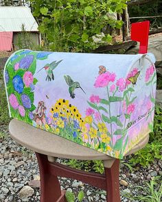 a painted mailbox sitting on top of a wooden bench