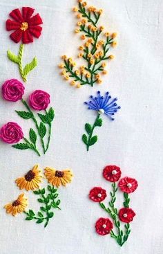 several different colored flowers on a white cloth