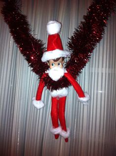 an elf doll hanging from the ceiling with red tinsel on it's arms