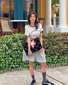 a woman standing in front of a building holding a purse