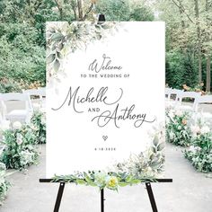 a white sign with greenery and flowers on it that says welcome to the wedding of michael and anthony