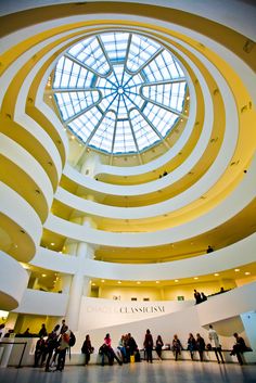 the inside of a building with people standing in it and looking up at the sky