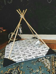 a teepee sitting on top of a rug in front of a blackboard