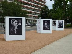 four black and white photographs on display in front of a building with trees near by