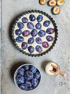 a pie with blueberries in it next to a bowl of nuts