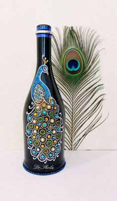 a bottle with a peacock painted on it next to a feather