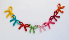 a multicolored crocheted ribbon necklace is displayed on a white surface,