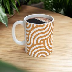 a cup of coffee sitting on top of a wooden table next to a potted plant