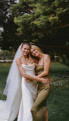 two women in wedding dresses hugging each other