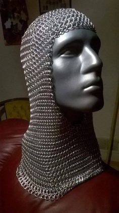 a mannequin with chains on it's head is shown in front of a red leather chair