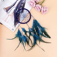 a blue dream catcher sitting on top of a table next to pink roses and a magazine