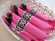 pink napkins with black and white monogrammed designs are arranged in a basket