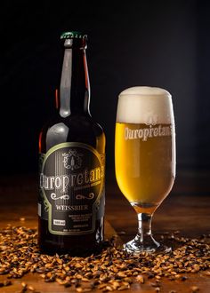 a bottle and glass sitting on top of a table next to some brown flakes