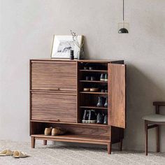 a wooden cabinet sitting next to a chair and table with shoes on top of it