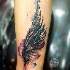 a watercolor feather tattoo on the left arm and leg, with blue ink splatters